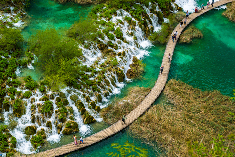 High Angle View Of People Walking On Boardwalk Over Water At Plitvice Lakes National Park